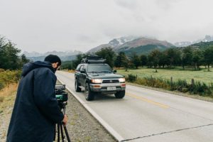 A photographer captures an SUV driving through the scenic mountains of Los Lagos, Chile.