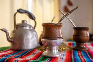 Close-up of yerba mate cups with kettle on colorful cloth, highlighting South American tradition.